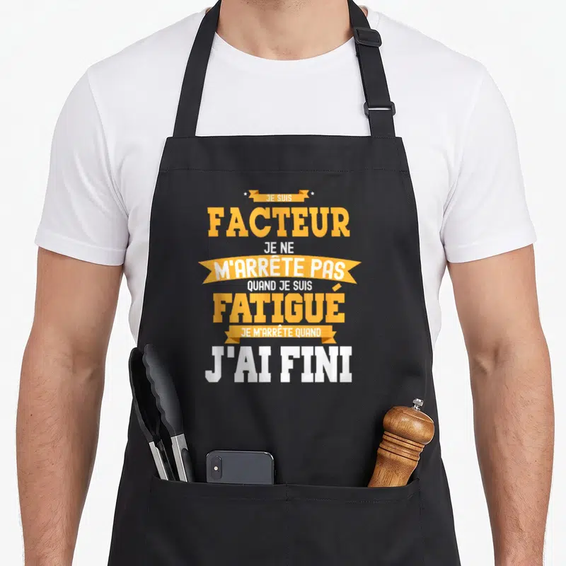Tablier de cuisine noir avec une inscription jaune et blanche affirmant être un facteur infatigable jusqu'à la fin des tâches.