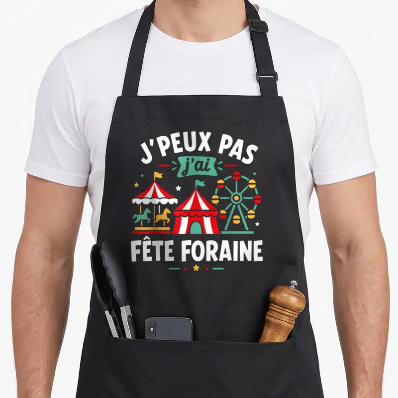 Tablier de cuisine noir avec inscription J'peux pas j'ai fête foraine et illustration de manège coloré.