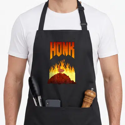 Tablier de cuisine noir avec inscription HONK et illustration d'un oiseau rouge sur un amas de crânes en feu.