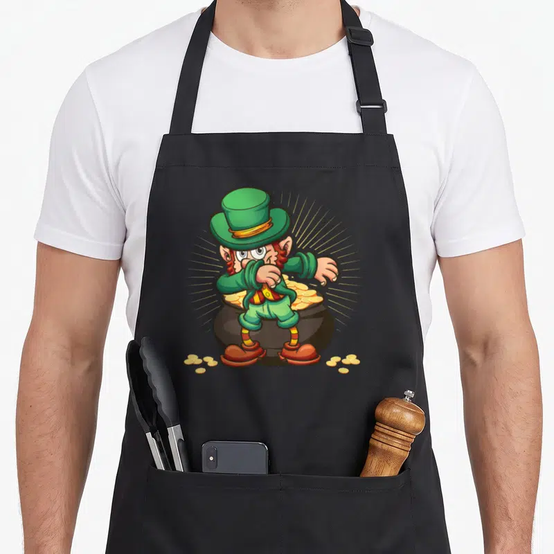 Tablier de cuisine noir avec un leprechaun vert en train de faire le dab au-dessus d'un pot de pièces d'or dorées.