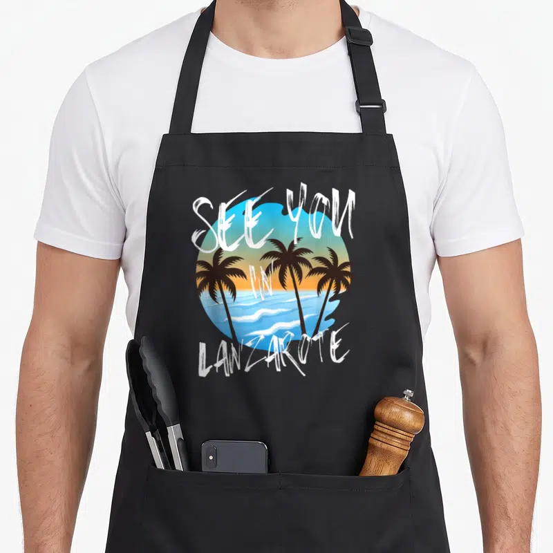 Tablier de cuisine noir avec illustration de palmiers et texte See You In Lanzarote sur fond de soleil couchant.