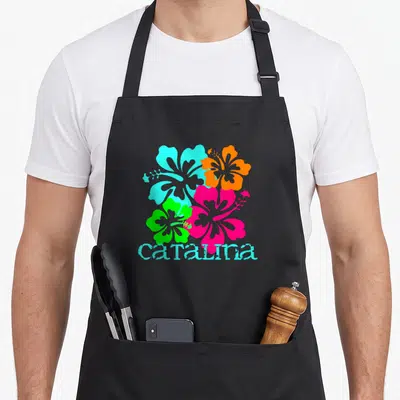Tablier de cuisine noir avec quatre hibiscus colorés et le mot catalina en turquoise stylisé.