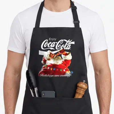 Tablier de cuisine noir avec Père Noël buvant du Coca-Cola entouré d'une guirlande lumineuse festive.