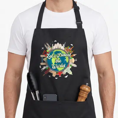 Tablier de cuisine noir avec globe terrestre et monuments internationaux autour du texte Let's Travel the World.