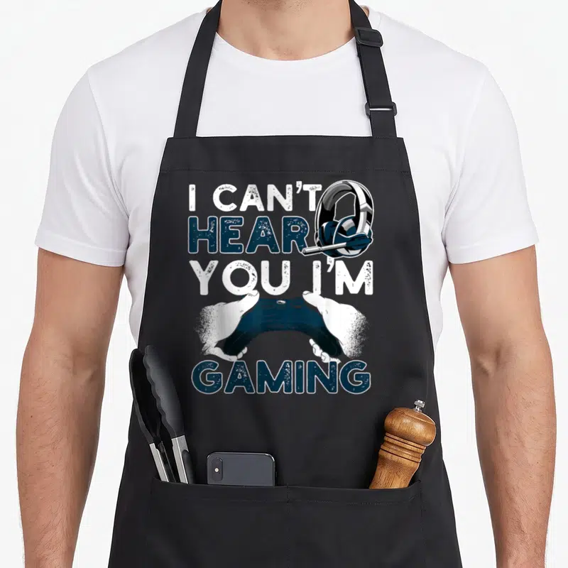 Tablier de cuisine noir avec une manette de jeu vidéo et des écouteurs imprimés en bleu et blanc.