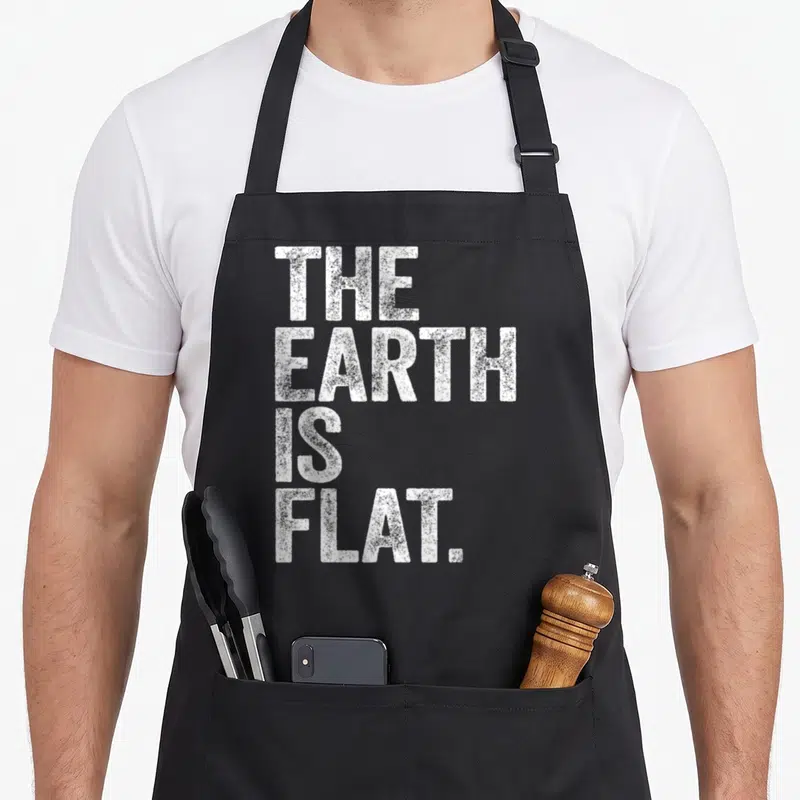 Tablier de cuisine noir avec inscription blanche THE EARTH IS FLAT en lettres capitales texturées.