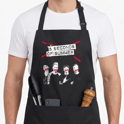 Tablier de cuisine noir avec illustration en noir et blanc de quatre visages barrés de croix rouges et le texte 5 SECONDS OF SUMMER.