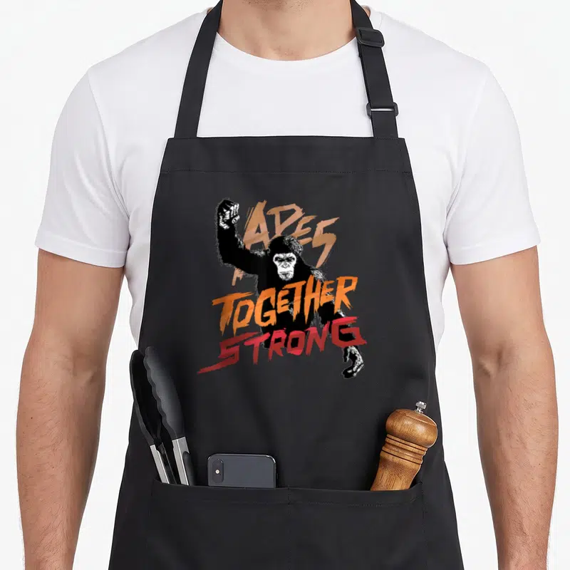 Tablier de cuisine noir avec illustration d'un gorille et texte Apes Together Strong en orange et rouge.