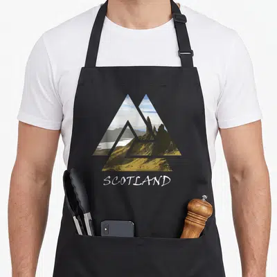 Tablier de cuisine noir avec illustration triangulaire du Sle of Skye et l'inscription SCOTLAND en blanc.