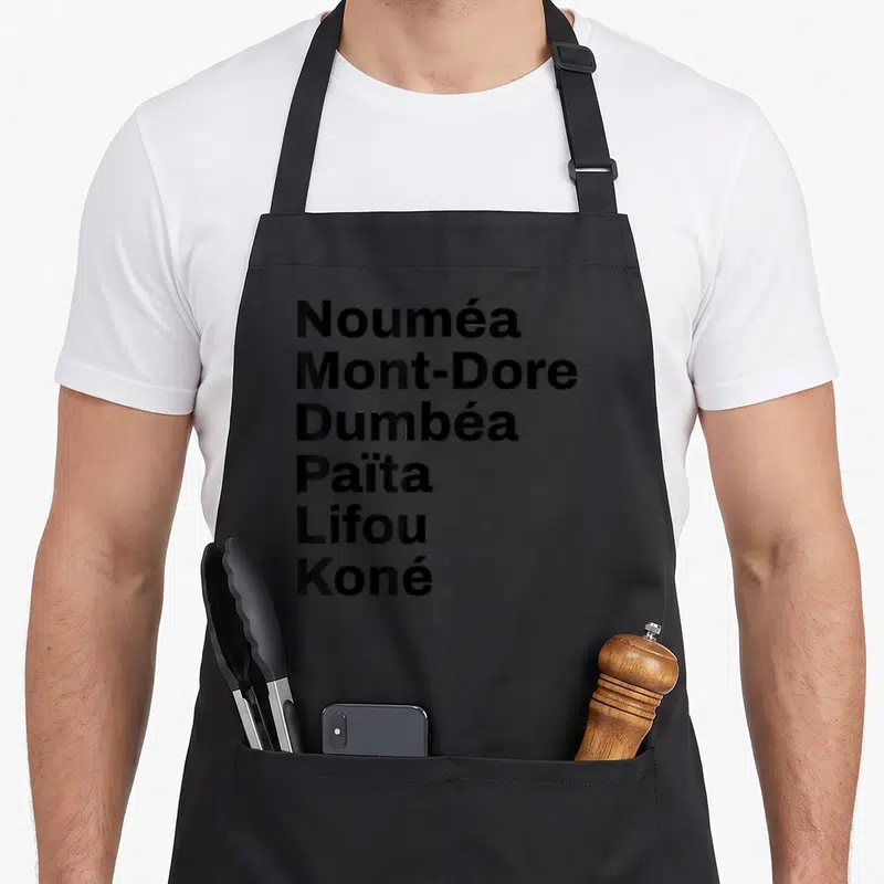 Tablier de cuisine noir avec une liste verticale de noms de lieux en Nouvelle-Calédonie en typographie noire.