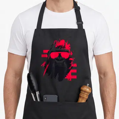 Tablier de cuisine noir avec illustration d'un gorille aux lunettes de soleil roses et éclaboussures graphiques rouges.