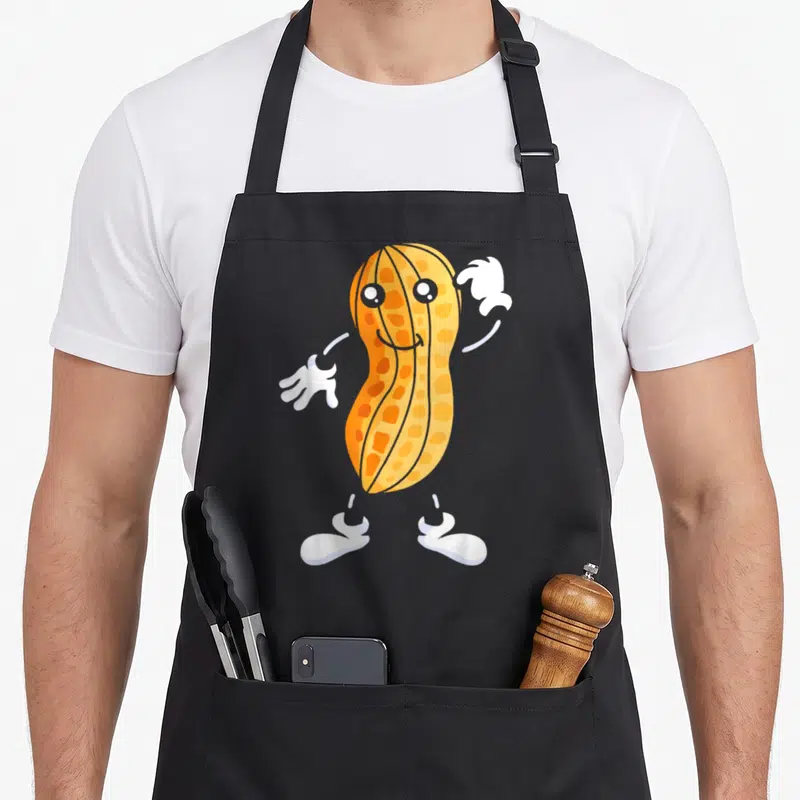 Tablier de cuisine noir avec une cacahuète orange souriante portant des gants et chaussures blancs.