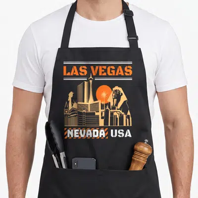 Tablier de cuisine noir avec illustration orange du skyline de Las Vegas Nevada USA incluant Sphinx et Stratosphere Tower.