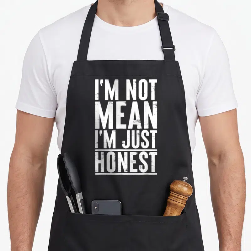 Tablier de cuisine noir avec le texte blanc « I'M NOT MEAN I'M JUST HONEST » imprimé au centre du torse.