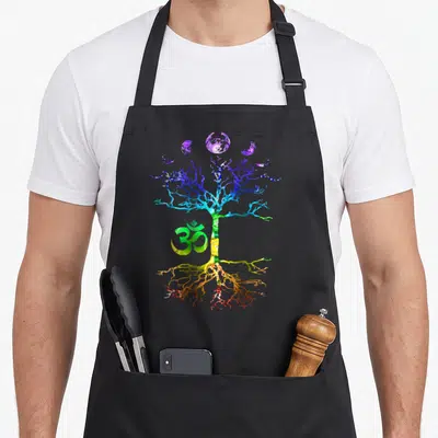 Tablier de cuisine noir avec un arbre multicolore, le symbole Om vert et des phases de lune violettes en haut.