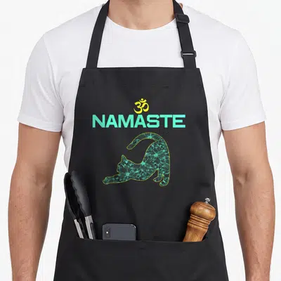 Tablier de cuisine noir avec illustration d'un chat aux motifs floraux sous le texte NAMASTE et le symbole OM jaune.