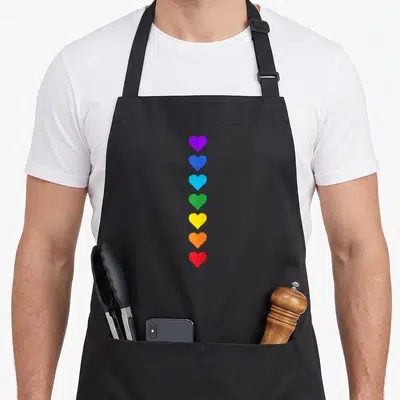 Tablier de cuisine noir avec sept cœurs colorés alignés verticalement représentant les chakras.