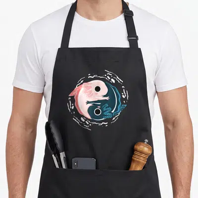 Tablier de cuisine noir avec illustration colorée de deux axolotls roses et bleus formant un cercle yin yang stylisé.