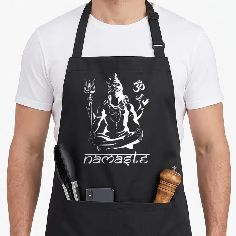 Tablier de cuisine noir avec illustration blanche d'une divinité assise en tailleur, un trident et le symbole om au-dessus du texte namaste.