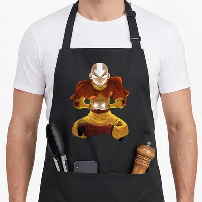 Tablier de cuisine noir avec Aang assis en tailleur, les mains émettant une lumière blanche intense.