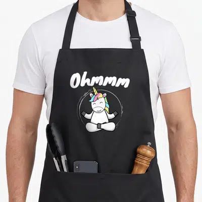 Tablier de cuisine noir avec une licorne blanche en position de yoga et le texte Ohmmm au-dessus.