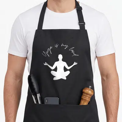 Tablier de cuisine noir avec silhouette blanche assise en tailleur et texte Yoga is my land au-dessus.