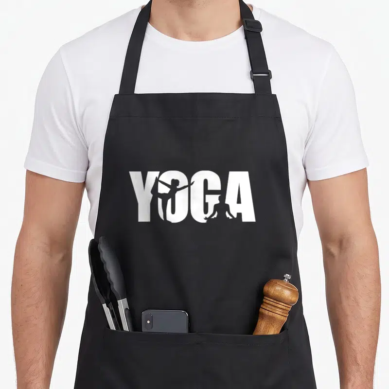 Tablier de cuisine noir avec le mot YOGA en blanc intégrant des silhouettes de personnes en postures d'étirement dans les lettres.