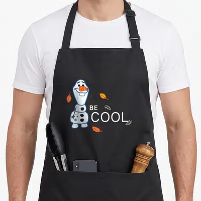 Tablier de cuisine noir avec Olaf Be Cool entouré de feuilles d'automne orange et noires.