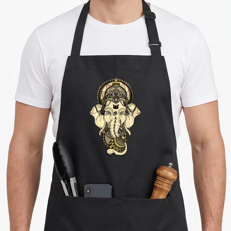 Tablier de cuisine noir avec illustration détaillée de la tête de Ganesha aux tons dorés et noirs.