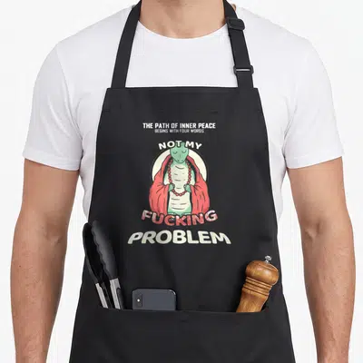 Tablier de cuisine noir avec une tortue en robe rouge et collier de prières, entourée de texte humoristique sur la paix intérieure.